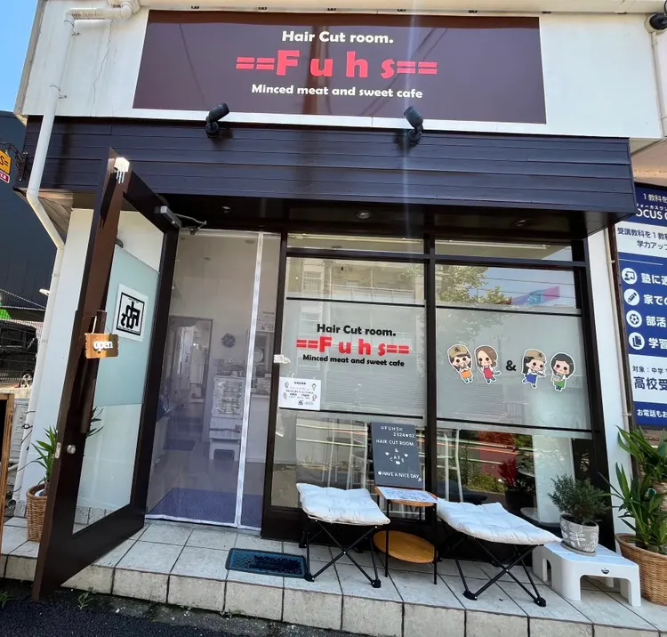 茶色の看板と、入口前にチェアが並ぶ==Fuhs==の外観